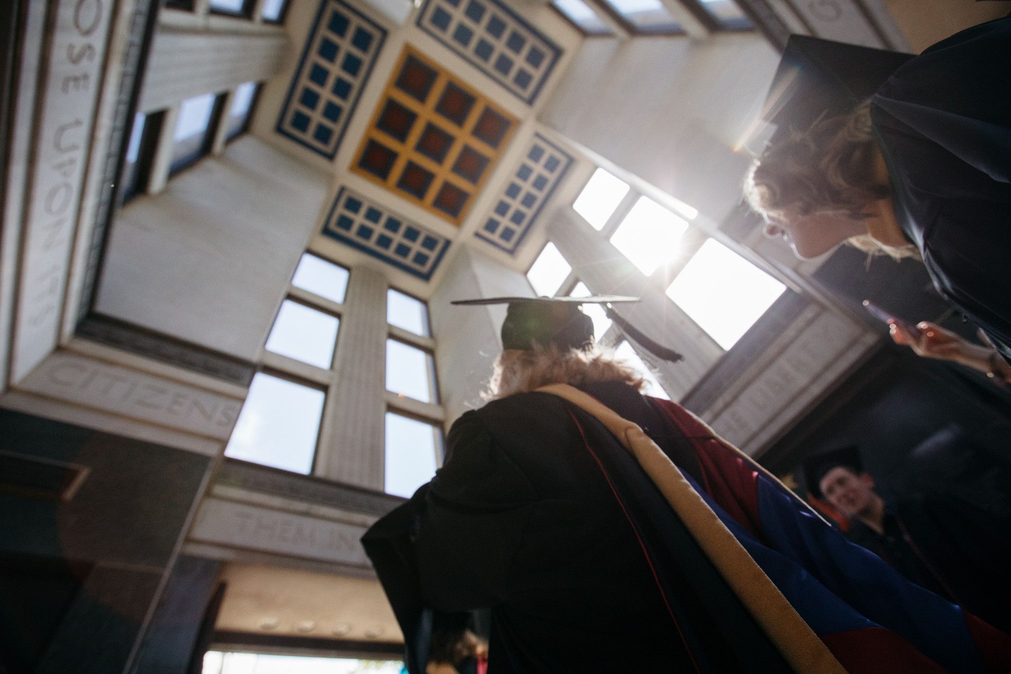 color photograph of graduates walking through University of Kansas Campanile during commencement ceremony. 