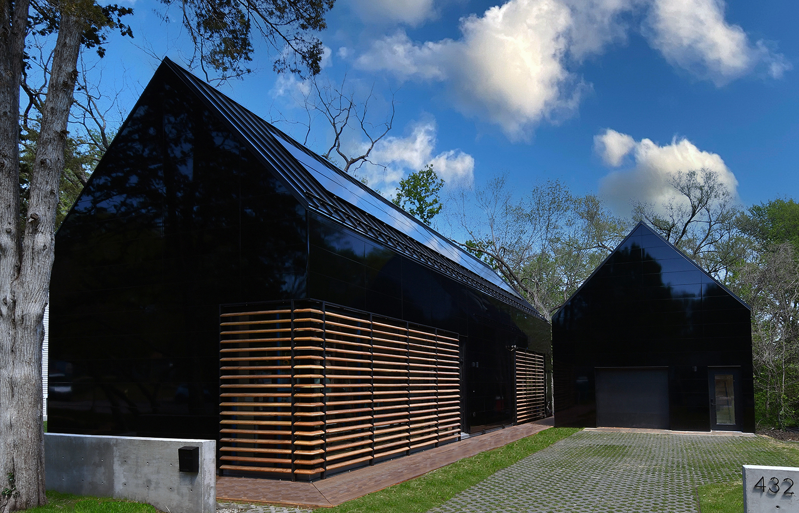 color photograph of modern home with gable roof clad in black, reflective siding. 