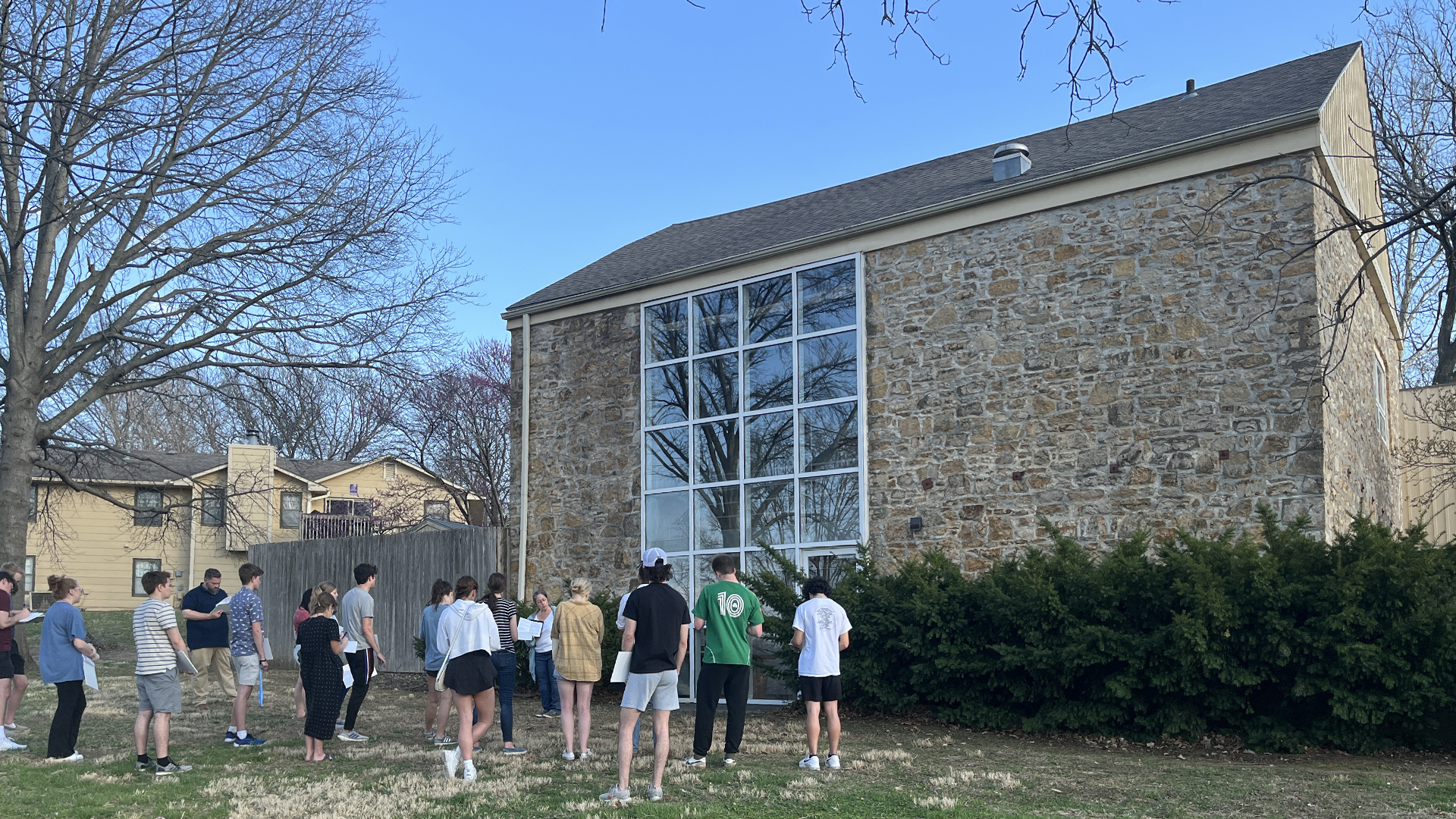 Color photograph shows Julia Manglitz and Steve Nowak presenting information in front of historic stone portion of Grover Barn, a documented site on the Underground Railroad. Students are listening to presenters.
